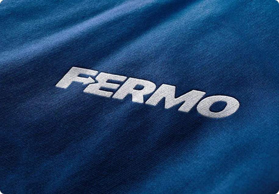 White Fermo logo embroided on a blue shirt.